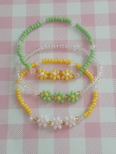 three beaded bracelets sitting on top of a pink and white checkered table cloth