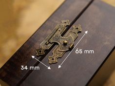 a wooden box with a metal cross on the inside and measurements in front of it