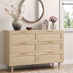 a white dresser sitting in front of a window next to a vase filled with flowers