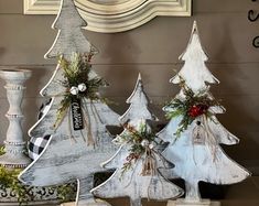 three wooden christmas trees sitting next to each other on a table in front of a clock