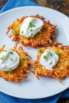 three potato cakes with sour cream on top are sitting on a white plate, ready to be eaten