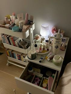 a white table topped with lots of beauty products and makeup bottles next to a bed