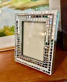 a mirror sitting on top of a wooden table next to a framed painting and other items