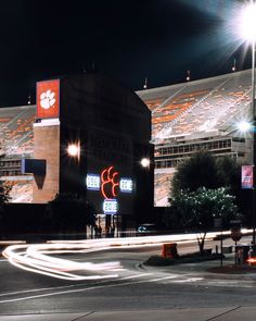 an empty parking lot at night in front of a stadium with lights and signs on it