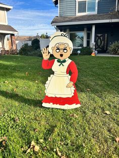 a lawn decoration in the shape of an old woman with glasses and a red dress