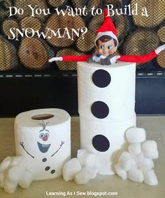 an elf is sitting on top of a roll of toilet paper next to a snowman