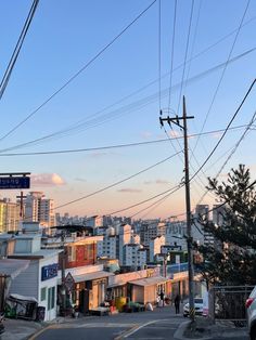 an empty street with power lines above it and buildings in the backgrouds