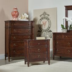 a bedroom scene with focus on the dresser and bed side table, mirror and vase