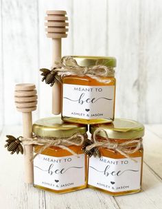 three jars of honey sitting on top of each other next to a wooden stick with a label that says meant to be