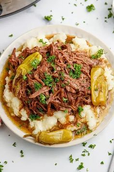 a white plate topped with meat and mashed potatoes covered in gravy next to an instant pressure cooker