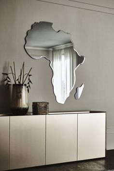 a mirror that is sitting on top of a dresser next to a vase with flowers