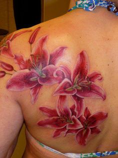 a woman's back tattoo with red flowers on her left shoulder and bottom part