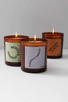 three candles sitting next to each other on a white surface with one candle lit up