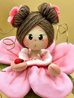 a little doll sitting on top of a pink flower