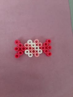 two red and one white circles on a pink surface with scissors in the middle that are connected to each other