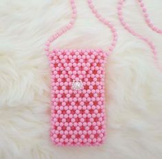 a pink beaded cell phone case sitting on top of a white fur covered floor