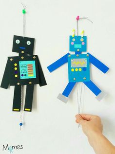 two paper toys are hanging from chains on a white background with the words robots en papie written below