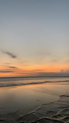 the sun is setting at the beach with waves coming in