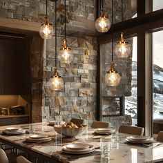 a dining room table with plates and bowls on it, lights hanging from the ceiling