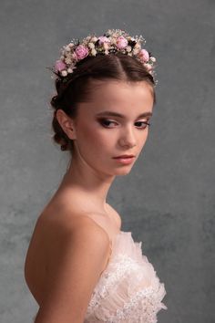 a young woman wearing a flowered headpiece in front of a gray background,