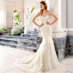 a woman in a white wedding dress standing next to some stairs and flowers on the steps