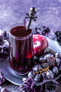 a glass filled with liquid sitting on top of a plate next to berries and flowers