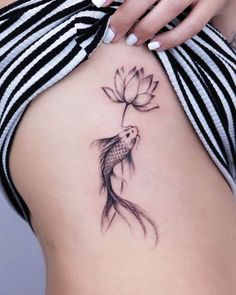 a woman's stomach with a fish and flower tattoo on her side ribcage