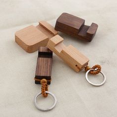 four wooden keychains are laying on the floor with one being held by a metal ring