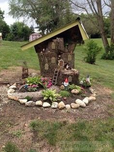 there is a fairy house in the middle of some rocks and flowers on the ground