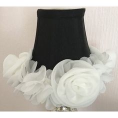 a black lamp shade with white flowers on the bottom, and a black lampshade behind it