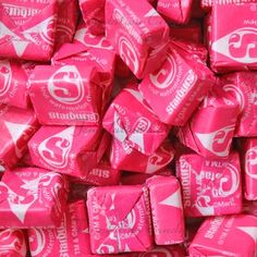 a pile of pink candies with white letters on them