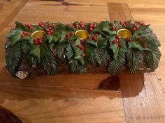 a wooden bench with holly and candles on the top, surrounded by red berries and green leaves