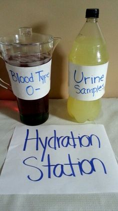 there are two bottles of liquid and a sign on the table that says hydration station