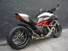 a silver and red motorcycle parked next to a wall