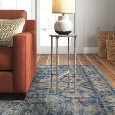 a living room with a couch, lamp and rug on the floor in front of it