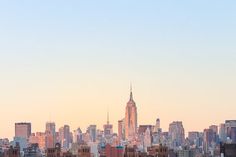 the skyline of new york city is shown at sunset with skyscrapers in the background