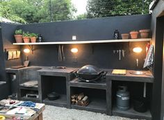 an outdoor bbq with potted plants and lights on the back wall is shown