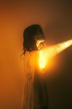 a woman standing in the dark with her head turned to the side holding a flashlight