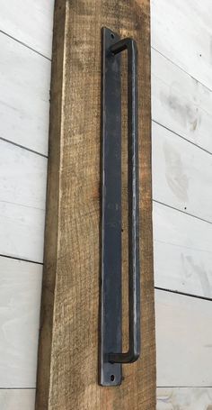 an old black door handle on a wooden board with white boards in the back ground