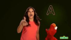 a woman in a red dress standing next to a sesame street character with an angry look on her face