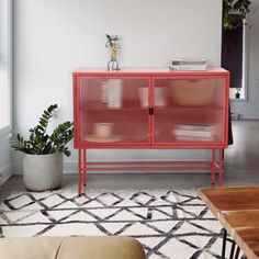 a living room with a red cabinet in the middle and a white rug on the floor