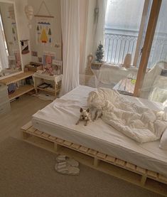 a small dog laying on top of a bed in a bedroom next to a window