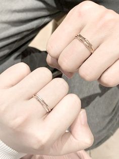 a person wearing two different rings on their fingers and one is holding the other hand