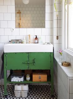 a bathroom with a sink, mirror and green cabinet in the middle of the room