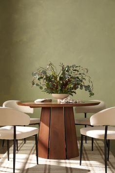 a dining room table with four chairs and a plant in the center on top of it