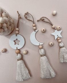 three tasseled ornaments are arranged next to a jar of beads and cotton balls