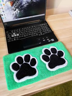 an open laptop computer sitting on top of a desk next to a pair of paw mats