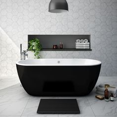 a black and white bathroom with hexagonal tiles on the walls, an oval bathtub in the foreground