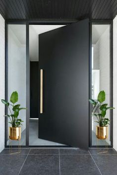 a black door with two gold planters in front of it