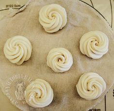 four white frosted pastries sitting on top of a cloth covered tray next to a ruler